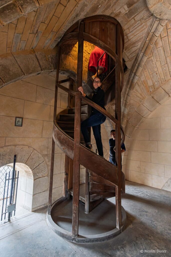 Visite guidée avec des touristes montant un escalier en colimaçon en pierre à Châlons-en-Champagne.