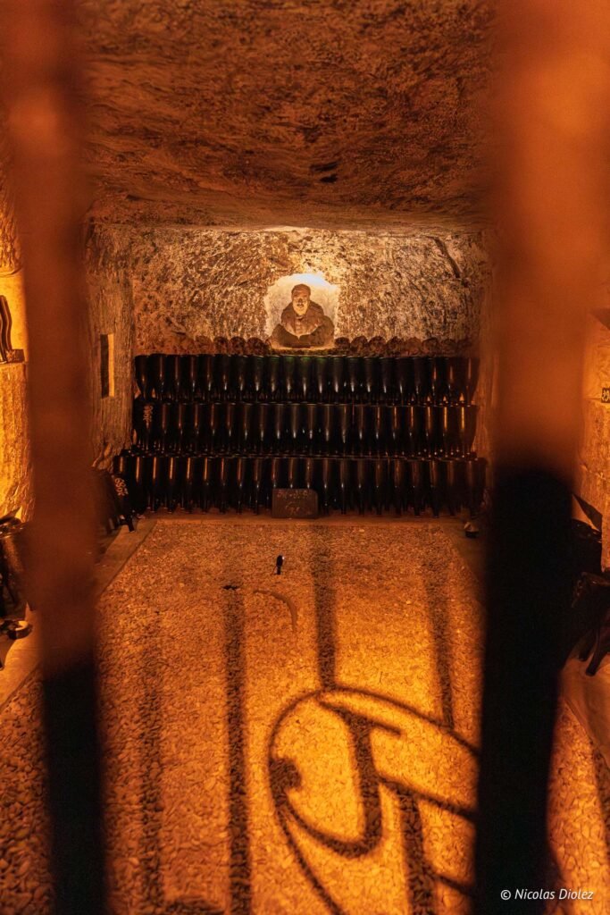 Cave de vieillissement Joseph Perrier à Châlons-en-Champagne avec bouteilles de champagne et portrait gravé dans la craie.
