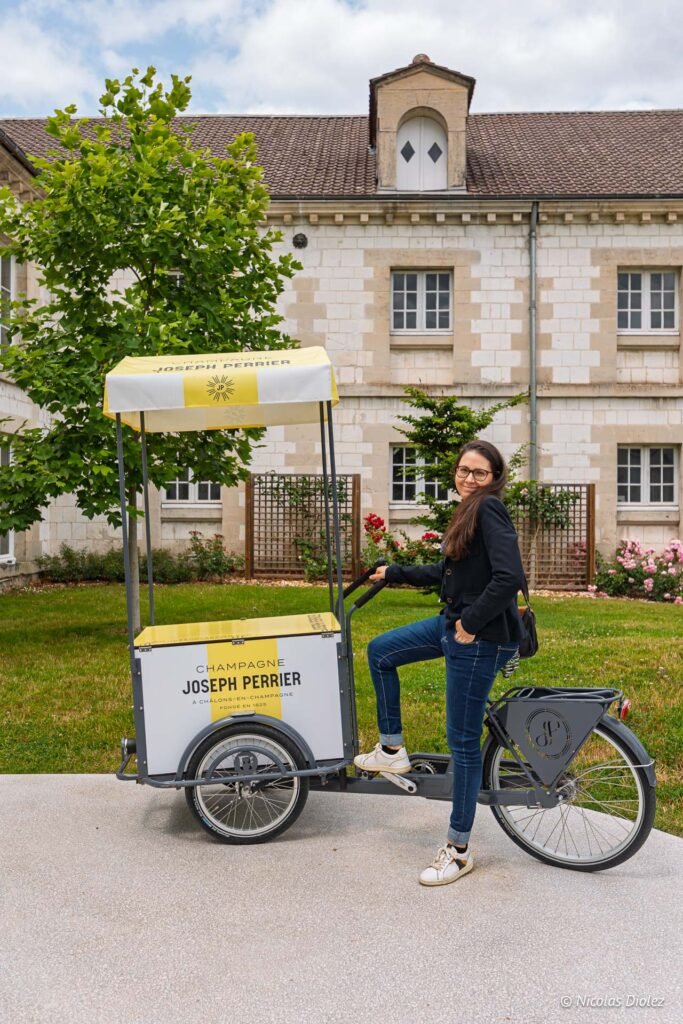 Femme posant à côté d'un vélo cargo de la maison de champagne Joseph Perrier à Châlons-en-Champagne.