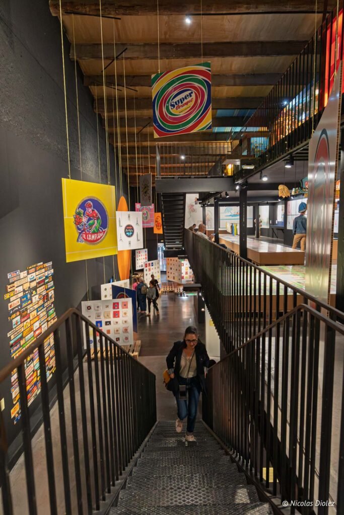 Visiteurs dans les espaces d'exposition du MIAM à Sète, incluant des œuvres suspendues et des collections graphiques au mur.