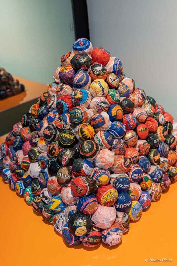 Pyramide composée de boules emballées dans des papiers colorés portant diverses inscriptions au musée MIAM de Sète.