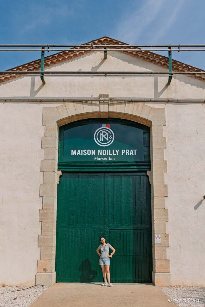 Visiteuse devant la porte d'entrée de la Maison Noilly Prat à Marseillan.