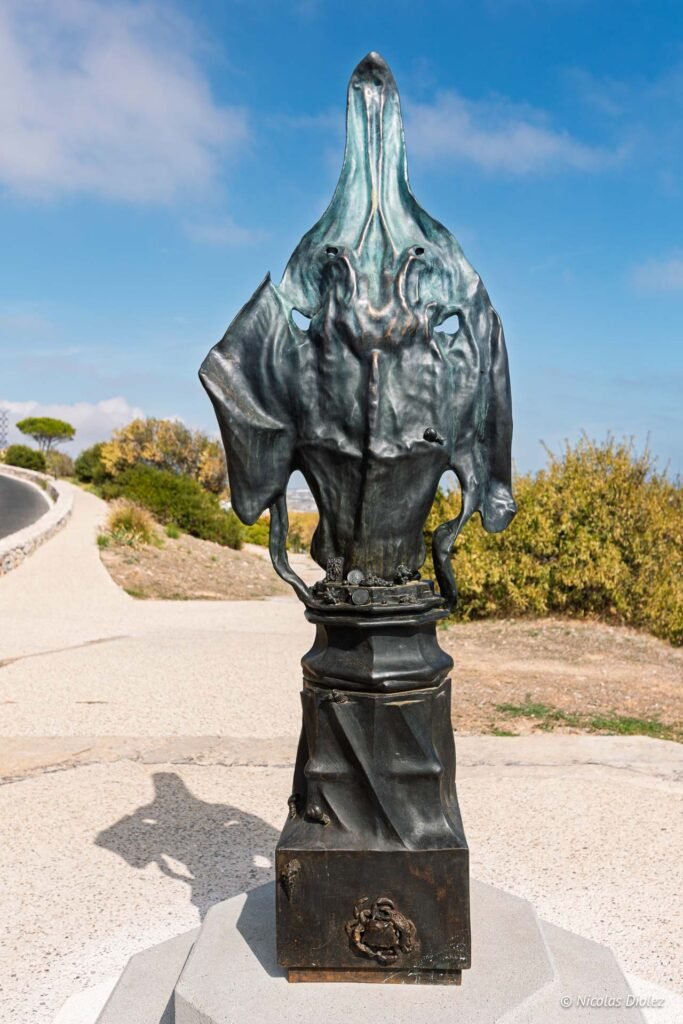 Sculpture en bronze sur le Mont Saint-Clair à Sète, entourée d'un sentier paysager sous un ciel bleu.
