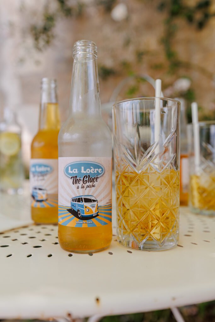 Bouteilles et verre de thé glacé à la pêche La Loère sur une table au Presbytère Maison Flore.