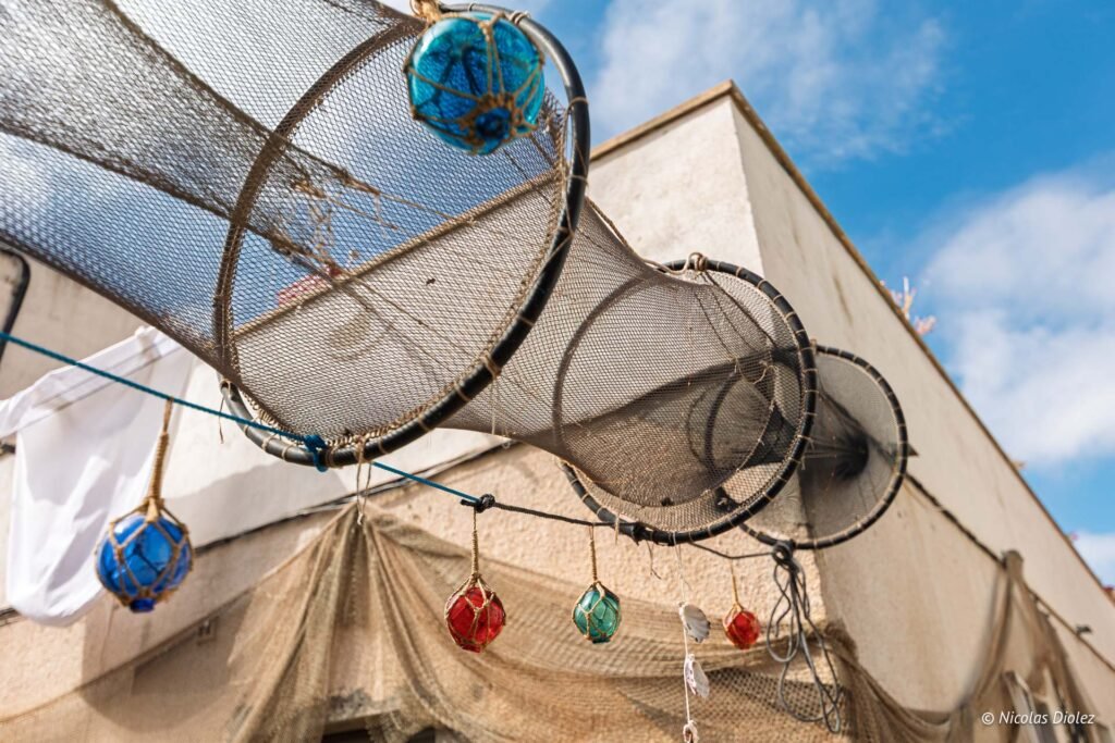 Filets de pêche traditionnels et flotteurs en verre suspendus dans le quartier de La Pointe Courte à Sète.