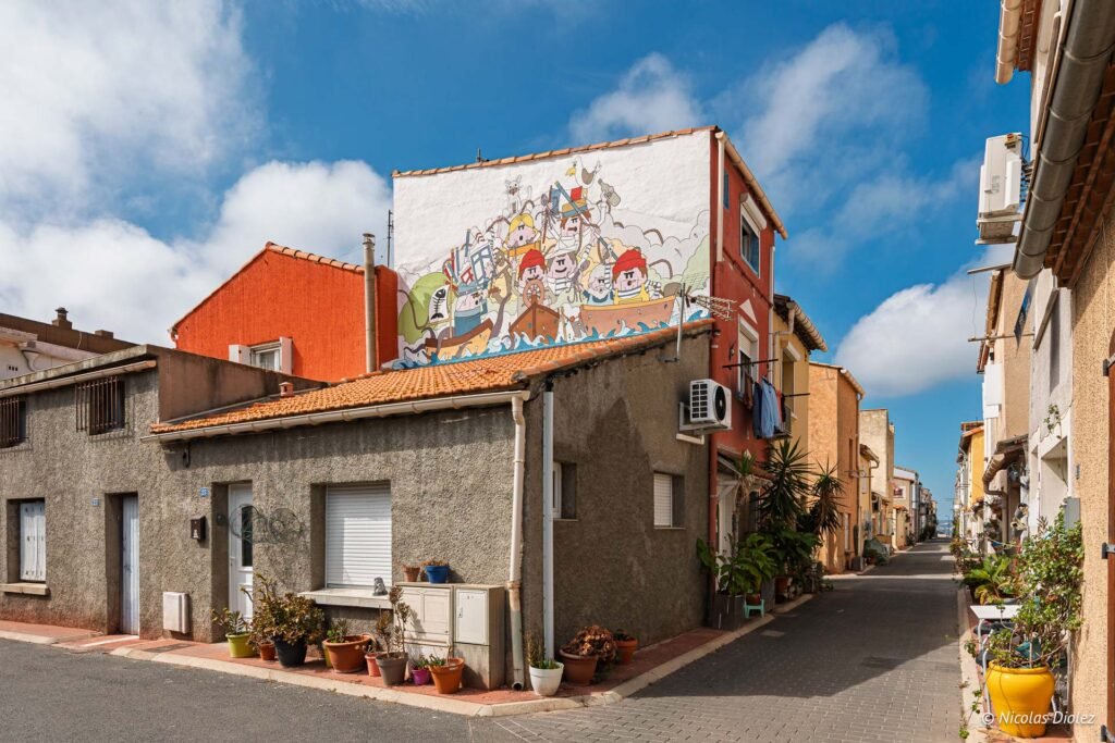 Maison de la Pointe Courte à Sète avec une fresque murale représentant des marins sur un bateau.