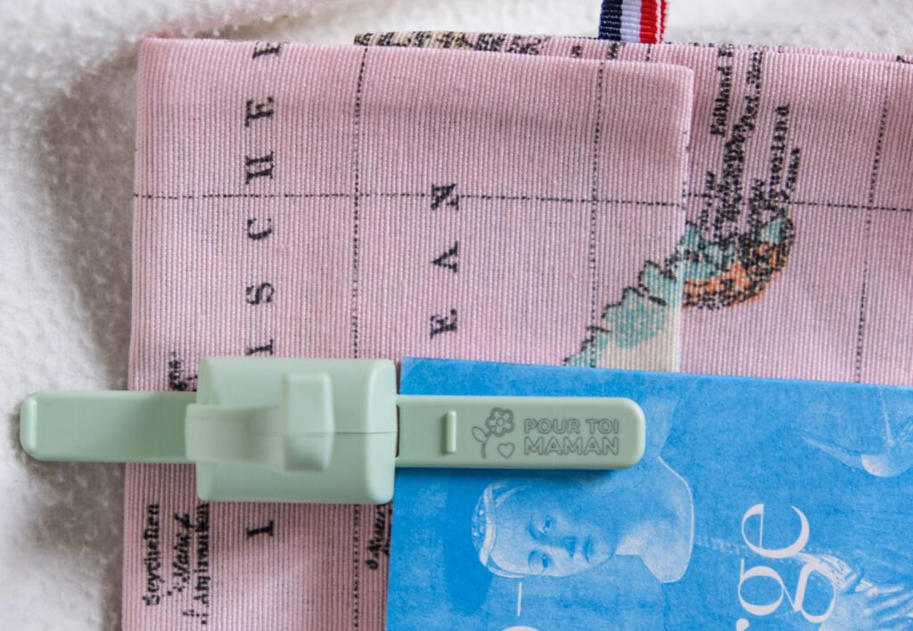 Pince à sachet verte avec l'inscription Pour toi maman posée sur un tissu rose à motif de carte mondiale.