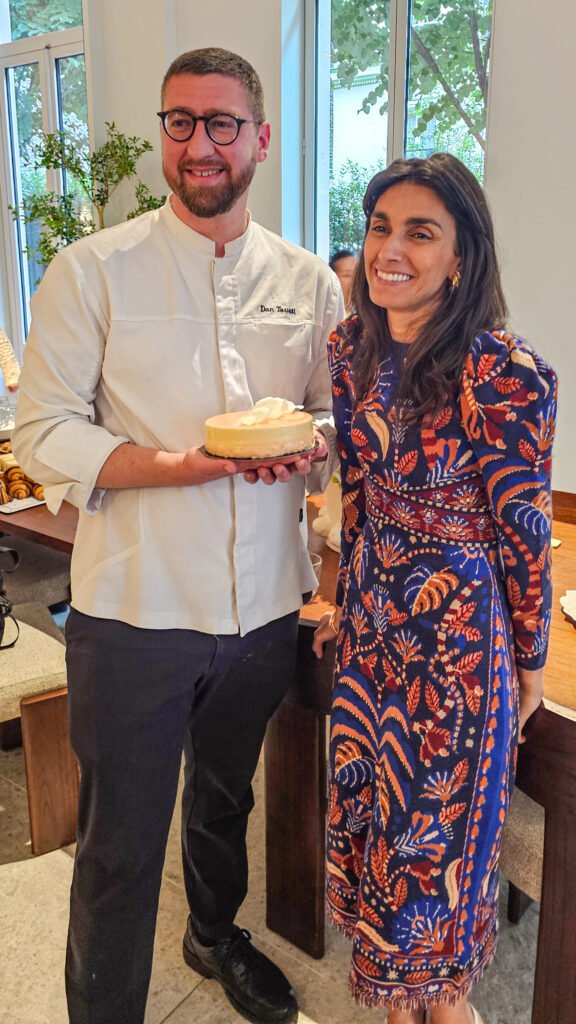 Le chef pâtissier Dan Touati présente un gâteau à côté d'une femme souriante dans un restaurant.