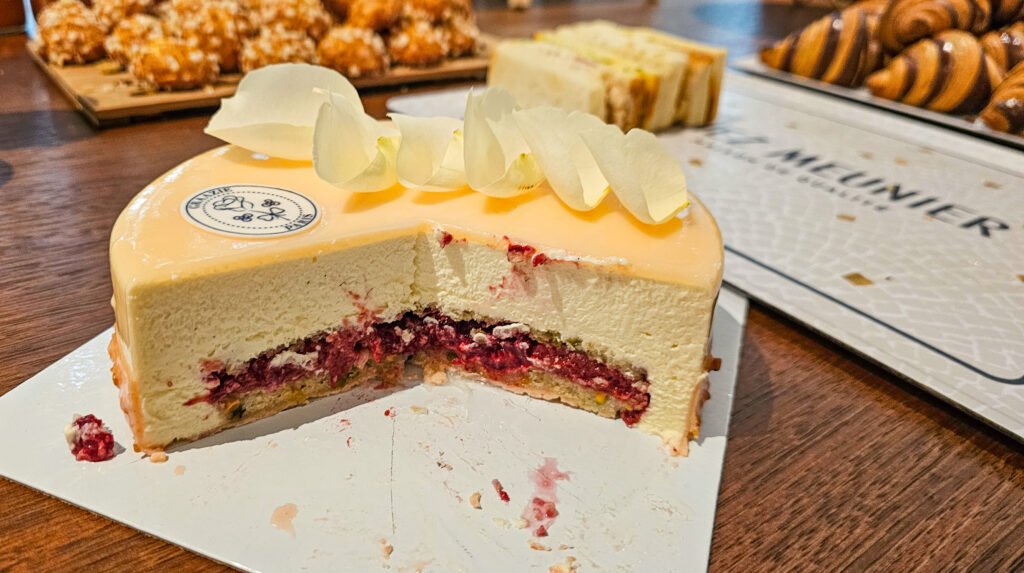 Entremets Meunier Graazie décoré de pétales, avec cœur fondant aux fruits rouges, sur un présentoir en carton.