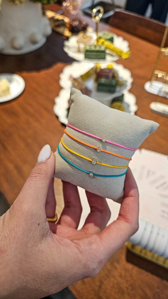 Main présentant quatre bracelets Meunier Graazie colorés sur un coussin gris avec des détails en diamants.
