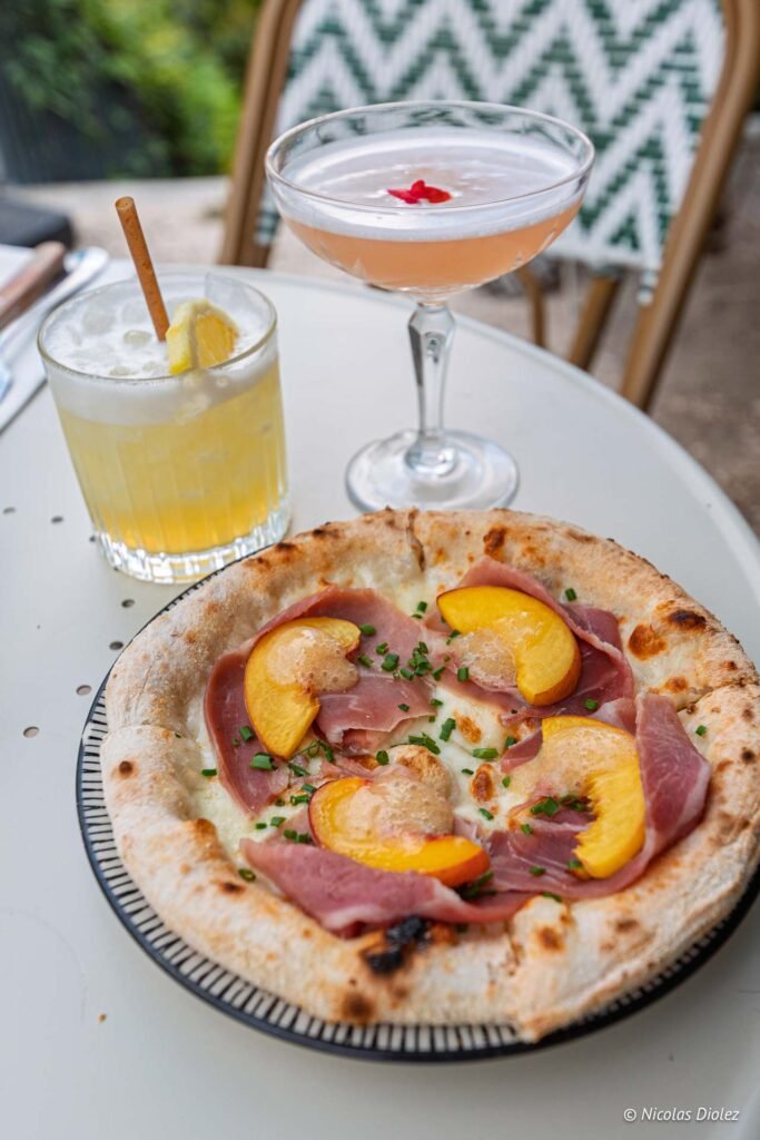 Pizza à la pêche et au jambon cru accompagnée de cocktails, collaboration Alain Milliat x Laïa Voltaire.