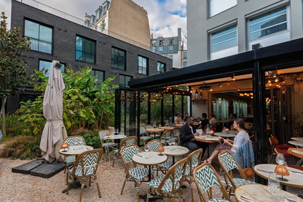 Terrasse du restaurant Laia à Paris avec des clients attablés, mobilier bistrot et ambiance chaleureuse en extérieur.