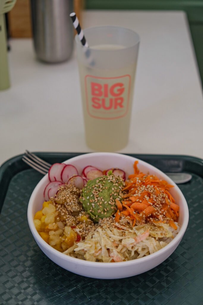 Poke bowl végétarien avec avocat et légumes frais et un verre de boisson marqué Big Sur.