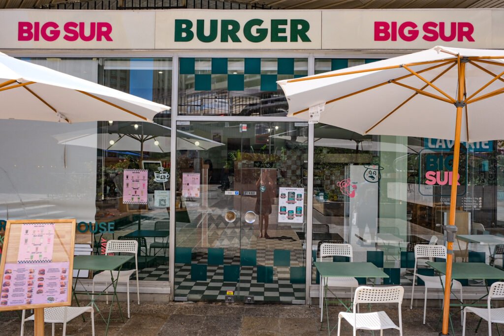 Façade du restaurant Big Sur Burger avec tables en terrasse et parasols blancs.