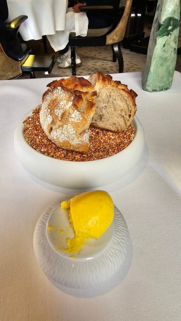 Pain artisanal au levain présenté sur un lit de sarrasin avec une portion de beurre frais au restaurant Gabriel.