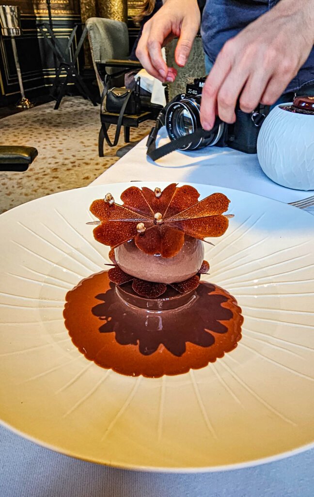 Dessert au chocolat raffiné en forme de fleur, servi dans une assiette élégante au restaurant Le Gabriel.