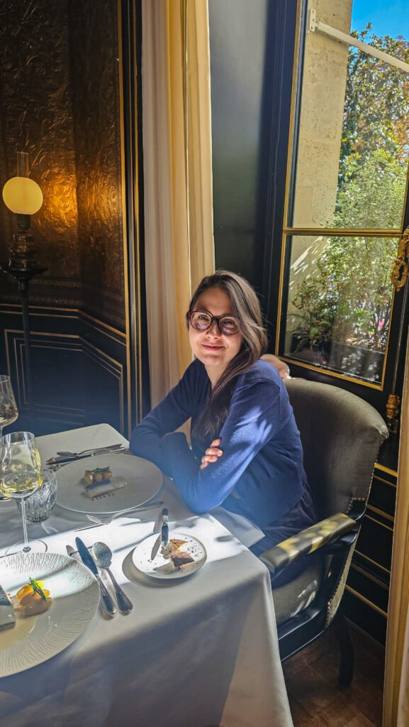 Femme souriante assise à une table élégante au restaurant Le Gabriel pour un déjeuner gastronomique.