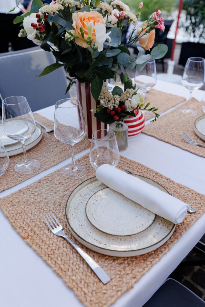 Table dressée avec des sets en jute, vaisselle en céramique et centre de table floral aux Jardins du Marais.