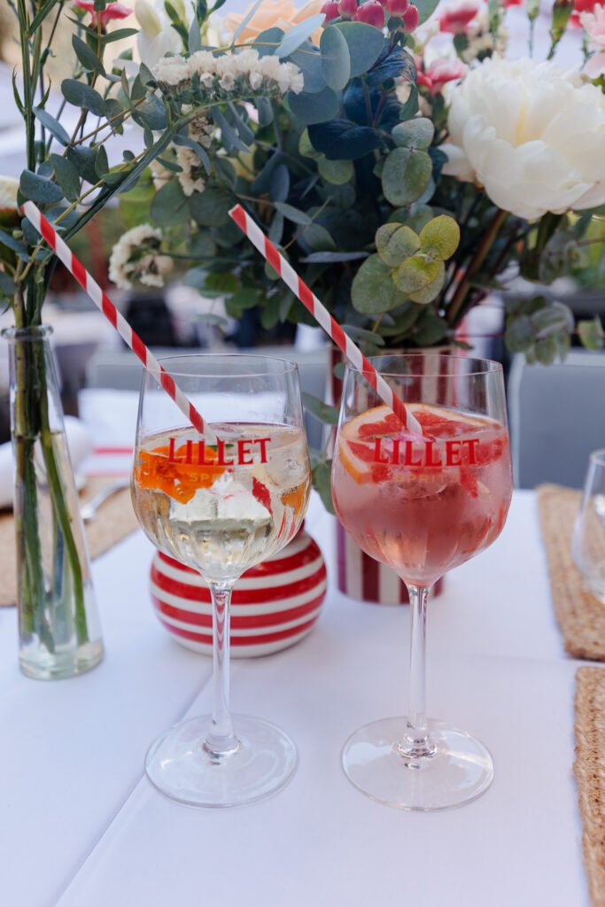 Deux verres de cocktail Lillet Spritz avec des pailles rayées sur une table décorée aux Jardins du Marais.