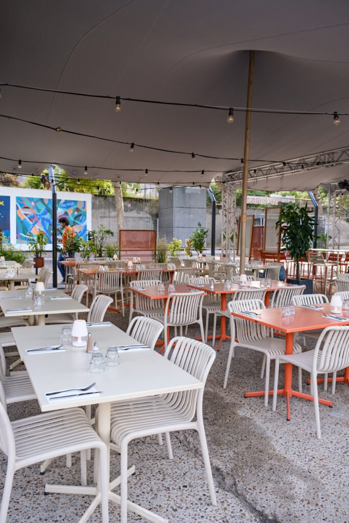 Terrasse extérieure du restaurant Plat-Form avec tables, chaises et éclairage guirlande sous une grande tente.