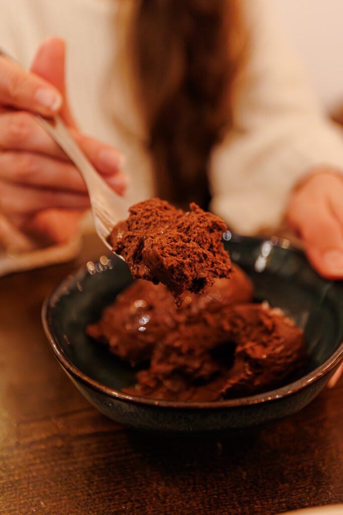 Persona che gusta una cremosa mousse al cioccolato in una ciotola al ristorante La Petite École a Parigi.