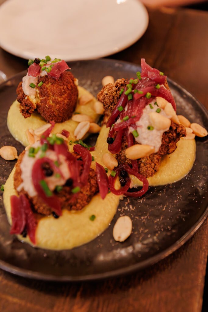 Piatto di cavolfiore arrosto con purè, cipolle rosse e arachidi servito al ristorante La Petite École a Parigi.