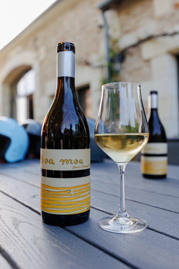 Bouteille de vin blanc Boa Moa avec verre sur une table en extérieur, Les Mobylettes de Marinette.