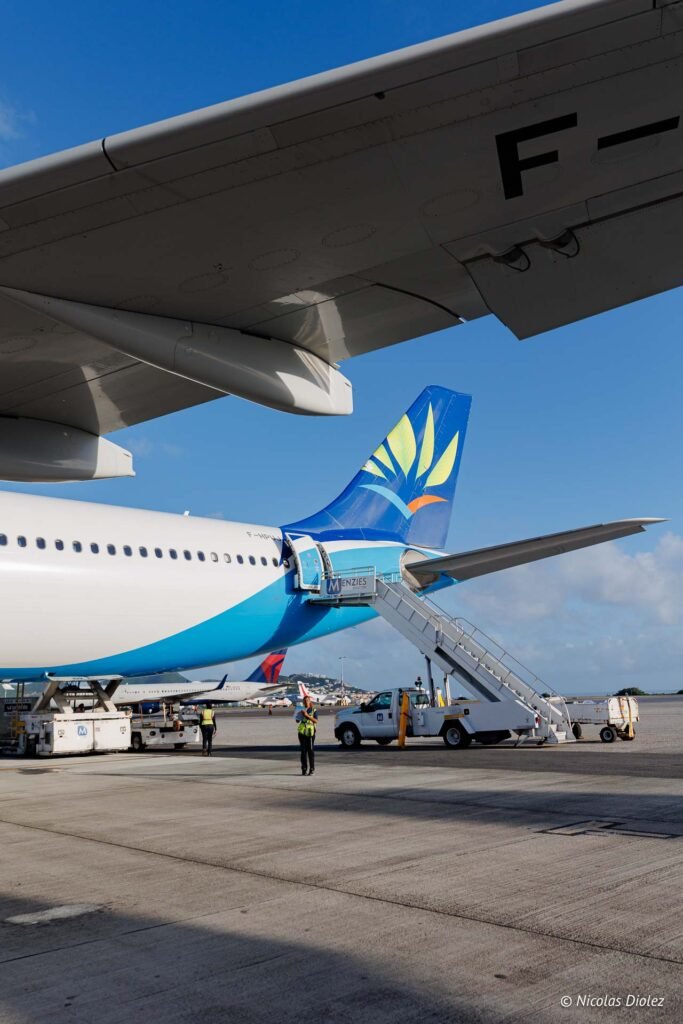Avion d'Air Caraïbes stationné sur le tarmac de l'aéroport de Saint-Martin avec une passerelle d'embarquement.