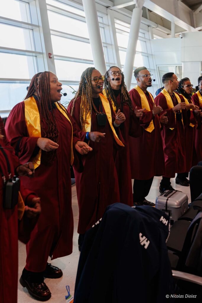 Chorale en tenues de cérémonie rouges et jaunes chantant lors du vol inaugural Air Caraïbes à Saint-Martin.