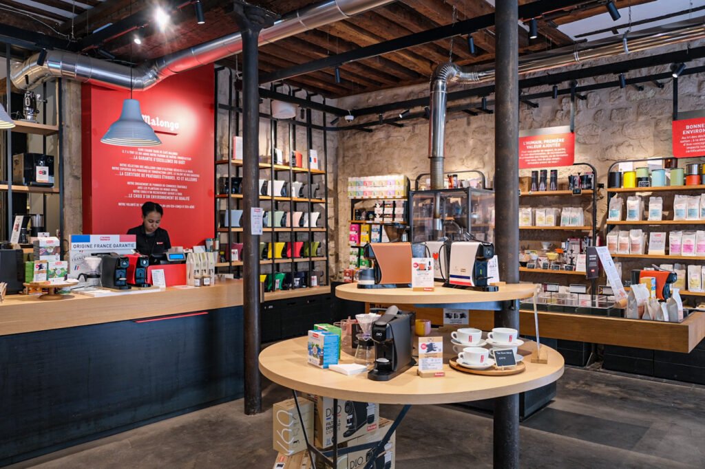 Interior of the Malongo boutique with barista at the counter and shelves filled with coffee machines and derivative products.