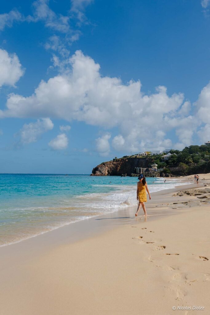 Femme marchant sur le sable de la plage de Baie Rouge à Saint-Martin.