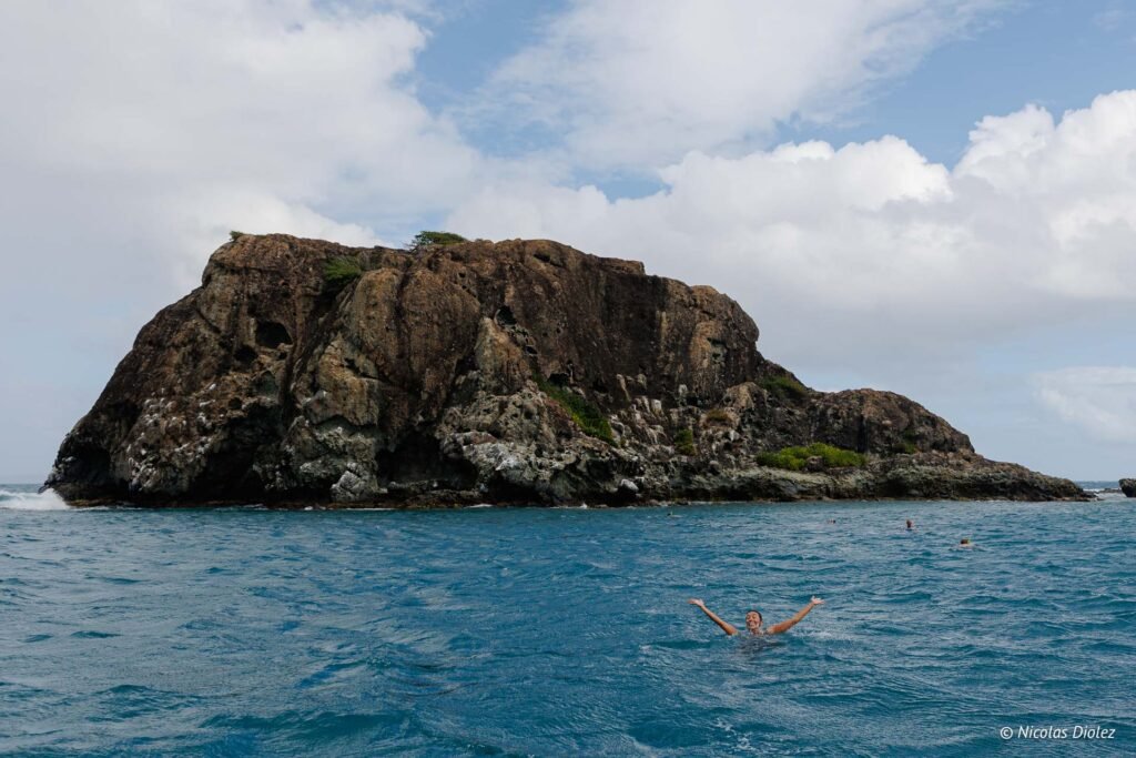Personne nageant dans la mer près d'un îlot rocheux lors d'une excursion en bateau à Saint-Martin.