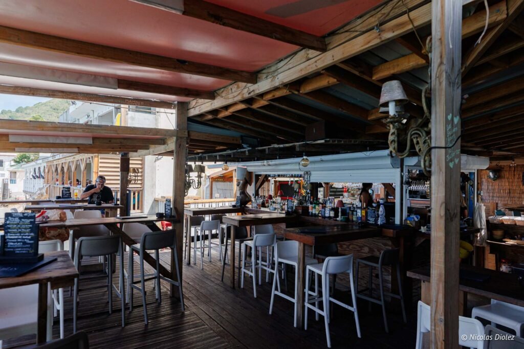 Terrasse couverte d'un bar-restaurant en bois avec tables et tabourets hauts à Grand-Case, Saint-Martin.