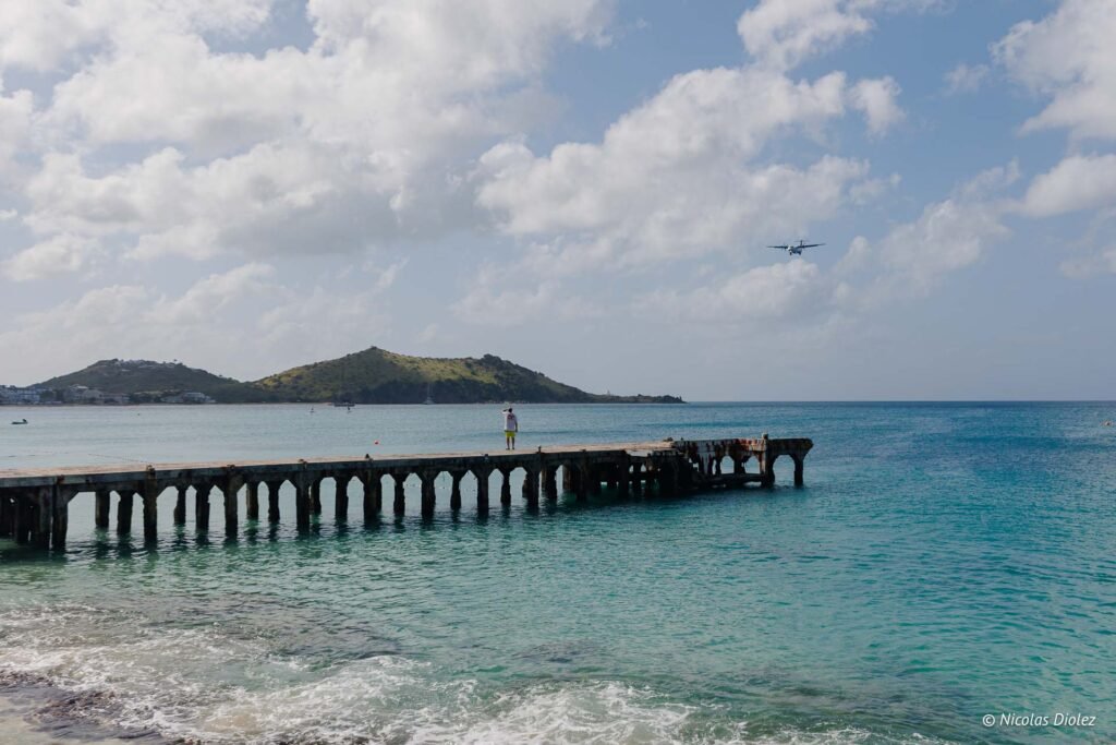 Personne sur le vieux ponton en béton à Grand-Case à Saint-Martin, avec un avion en approche.