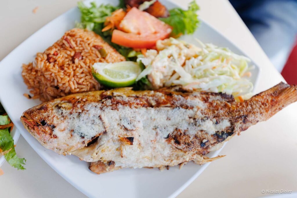 Plat traditionnel antillais à Saint-Martin avec du poisson grillé nappé de sauce, du riz, de la salade et du colombo.