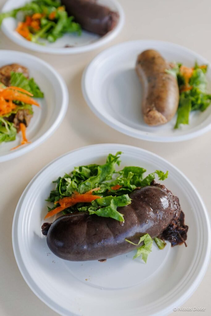 Assiettes en plastique blanc garnies de boudin noir créole et de salade verte à Grand-Case à Saint-Martin.