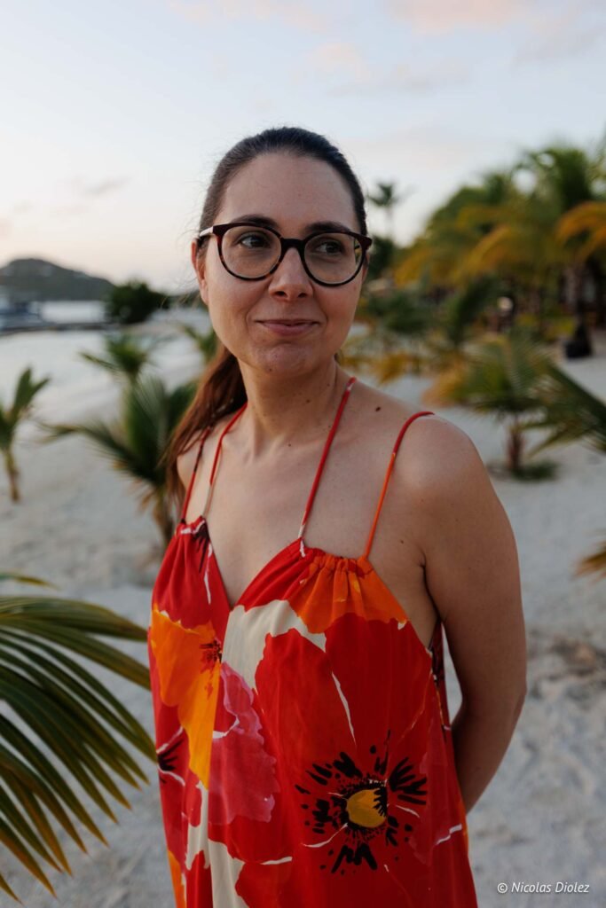 Femme souriante en robe fleurie posant sur une plage de l'hôtel Hommage à Saint-Martin.