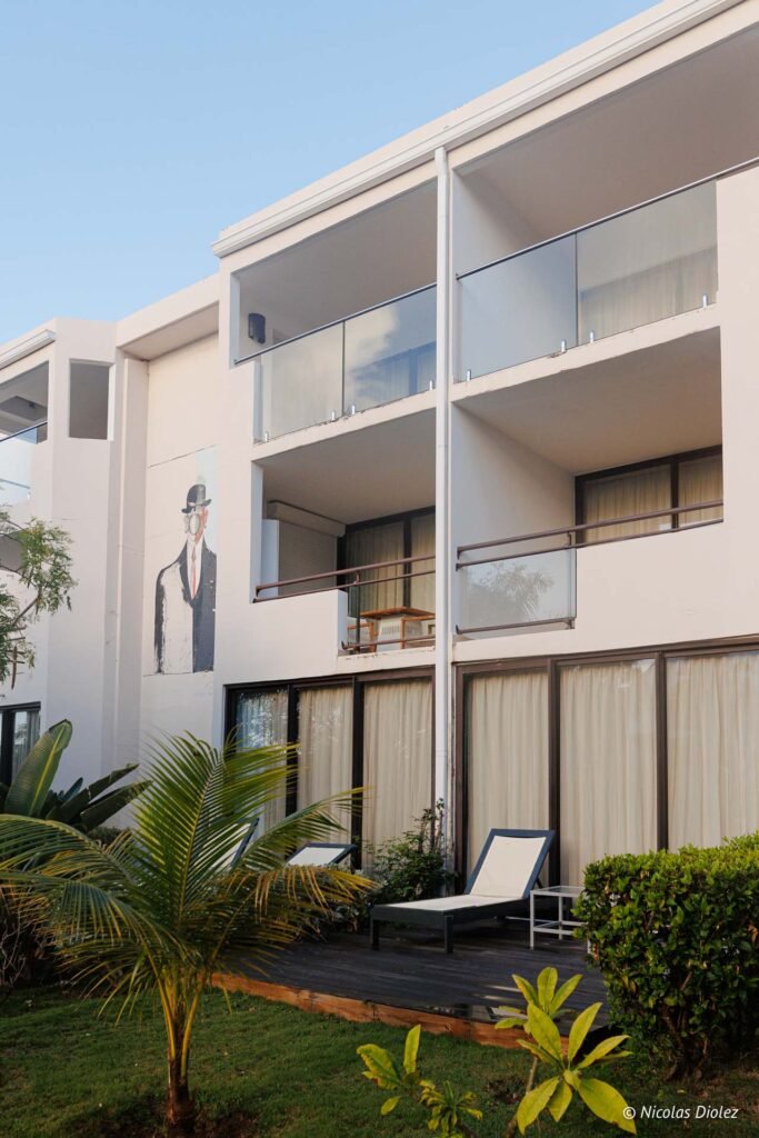 Façade de l'hôtel Hommage Saint-Martin avec balcons, fresque murale et transats sur la terrasse extérieure.