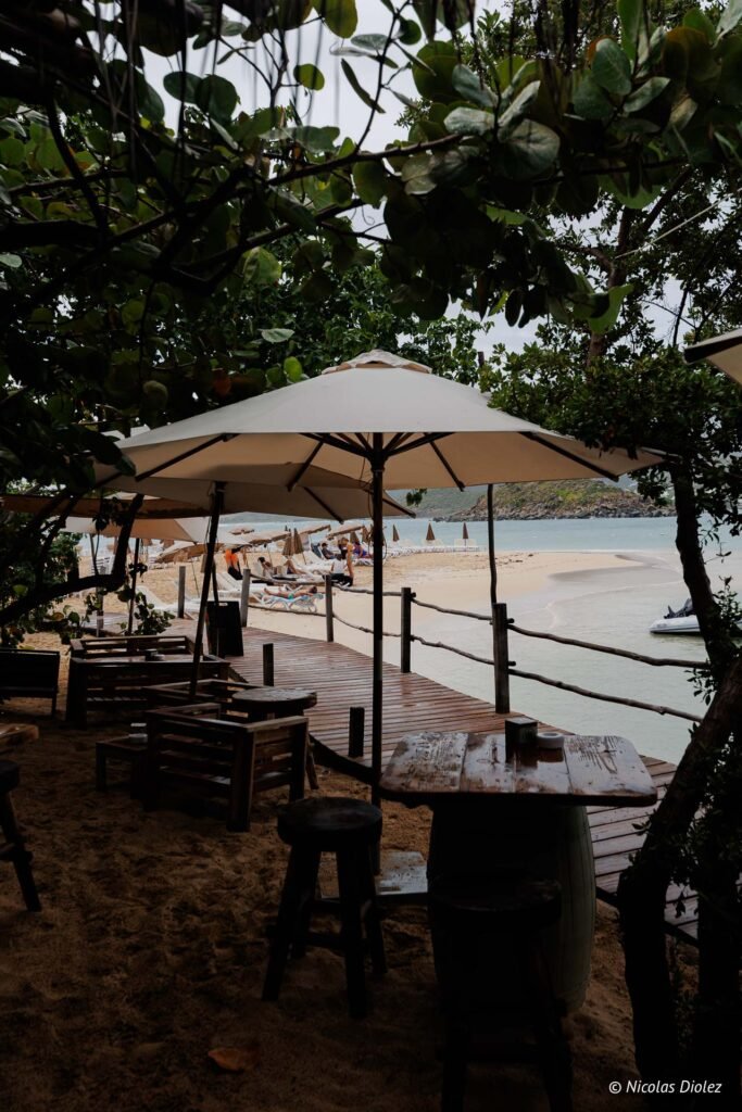 Terrasse en bois d'un restaurant de plage ombragée par des parasols sur l'îlet Pinel à Saint-Martin.