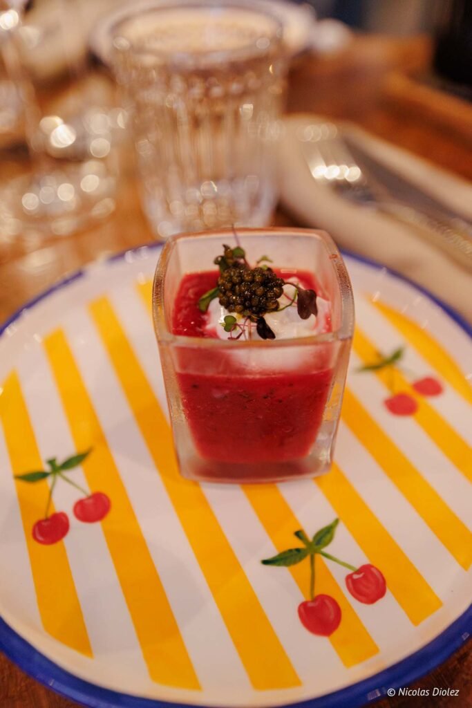 Verrine gastronomique au coulis rouge surmontée de caviar et de crème, servie au restaurant Le Temps des Cerises.