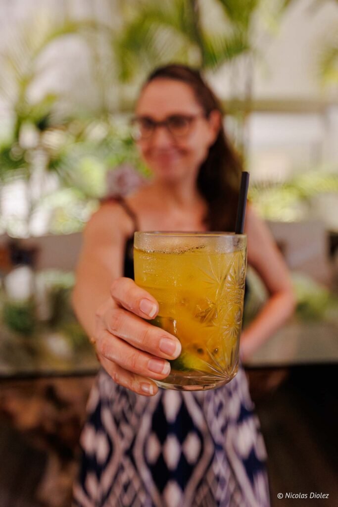 Cliente tenant un cocktail frais avec une paille à l'hôtel Le Temps des Cerises à Saint-Martin.
