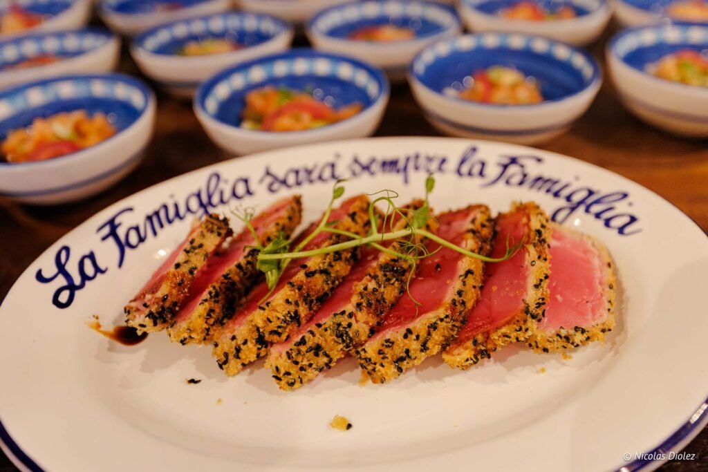 Tranches de thon mi-cuit en croûte de sésame servies sur une assiette avec l'inscription La Famiglia sarà sempre la famiglia.
