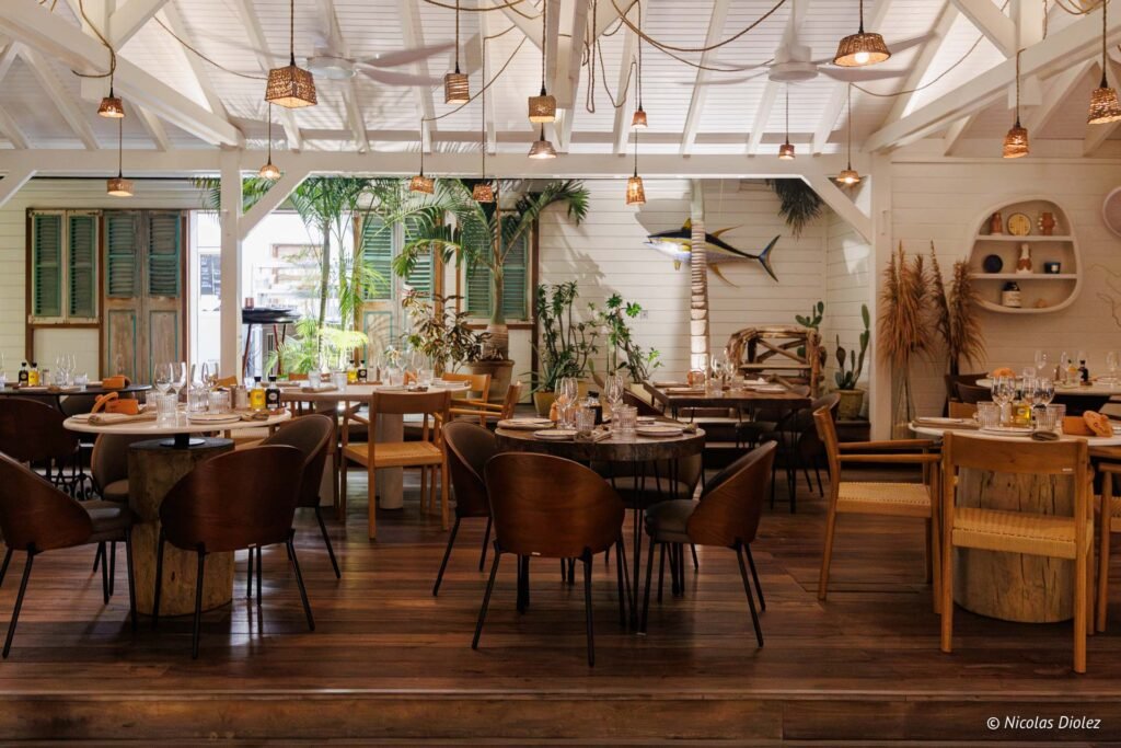 Intérieur lumineux du restaurant Le Temps des Cerises à Saint-Martin avec des tables en bois et des suspensions en osier.