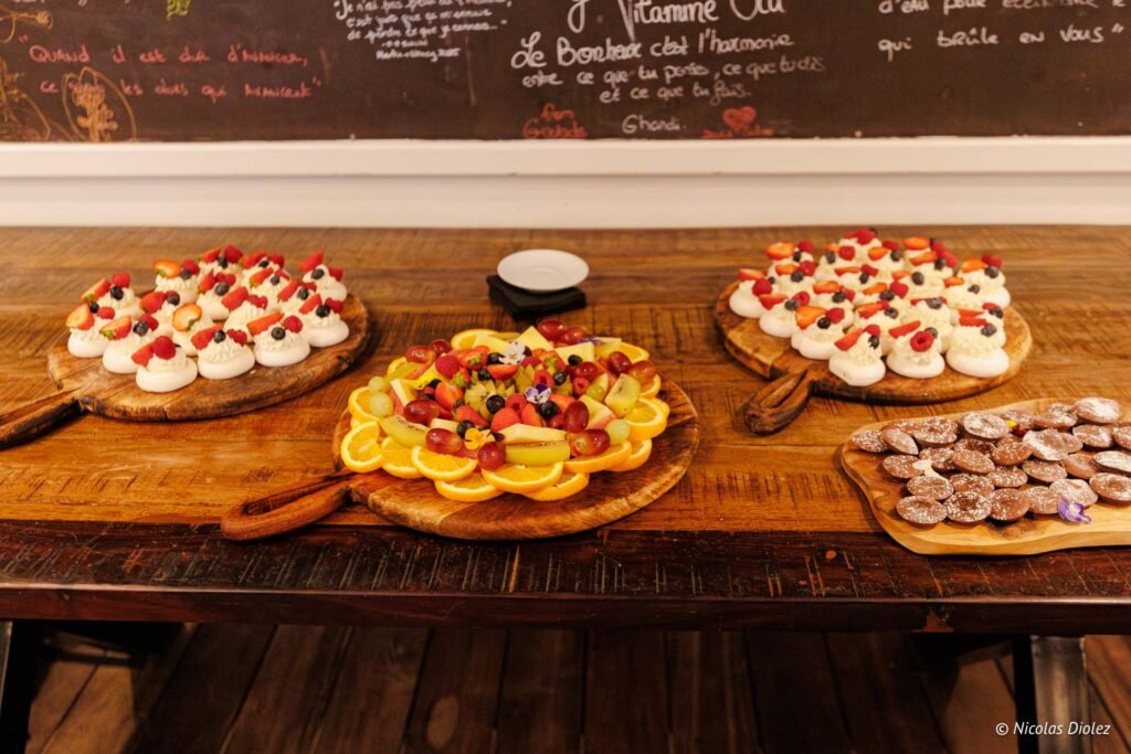 Plateaux en bois dressés de desserts variés, meringues aux fruits rouges, plateau de fruits frais et biscuits.