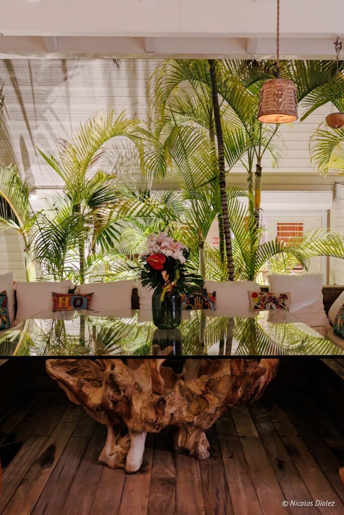Grande table en bois sculpté avec plateau en verre au restaurant Le Temps des Cerises à Saint-Martin.