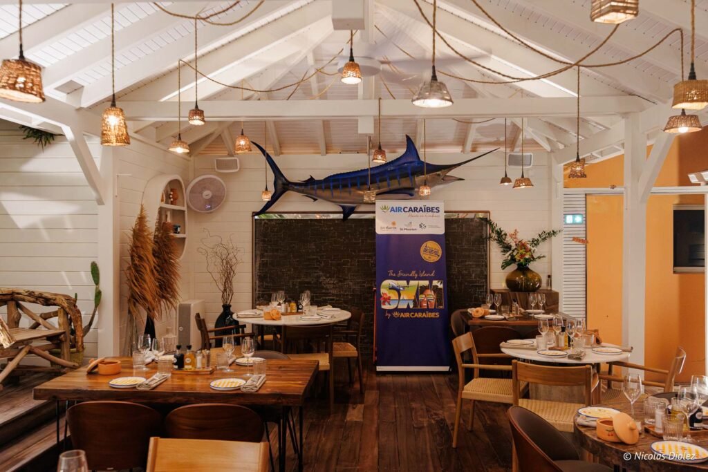 Intérieur du restaurant Le Temps des Cerises à Saint-Martin avec tables dressées et marlin sculpté au mur.