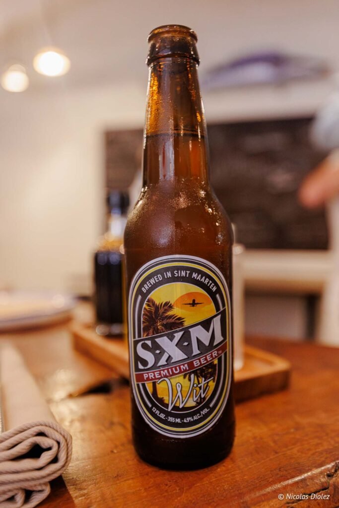 Bouteille de bière SXM Premium Beer Wit posée sur une table en bois à Saint-Martin.