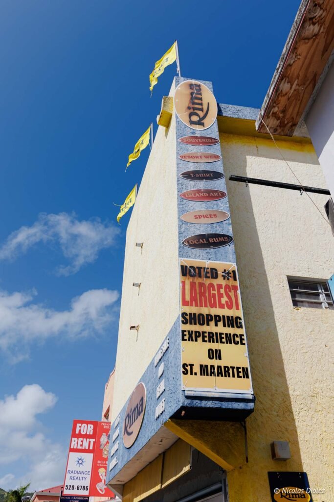 Enseigne verticale du magasin Rima, plus grand centre commercial de Sint Maarten, sous un ciel bleu.