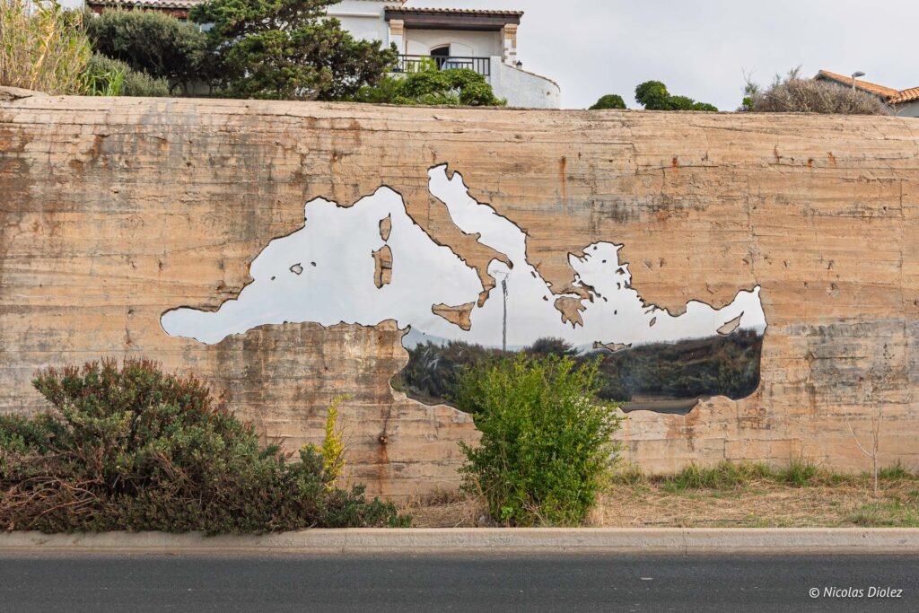 Miroir en forme de carte de la mer Méditerranée incrusté dans un mur en béton à Sète.