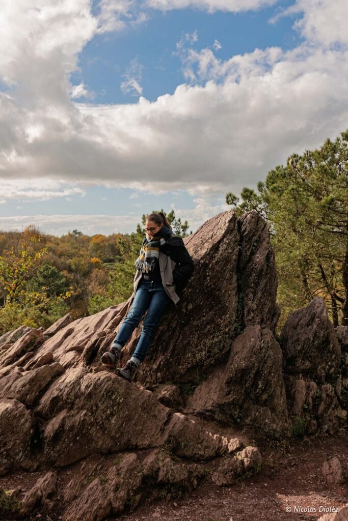 Randonneuse posée sur un grand rocher lors d’une visite guidée de la forêt de Brocéliande.